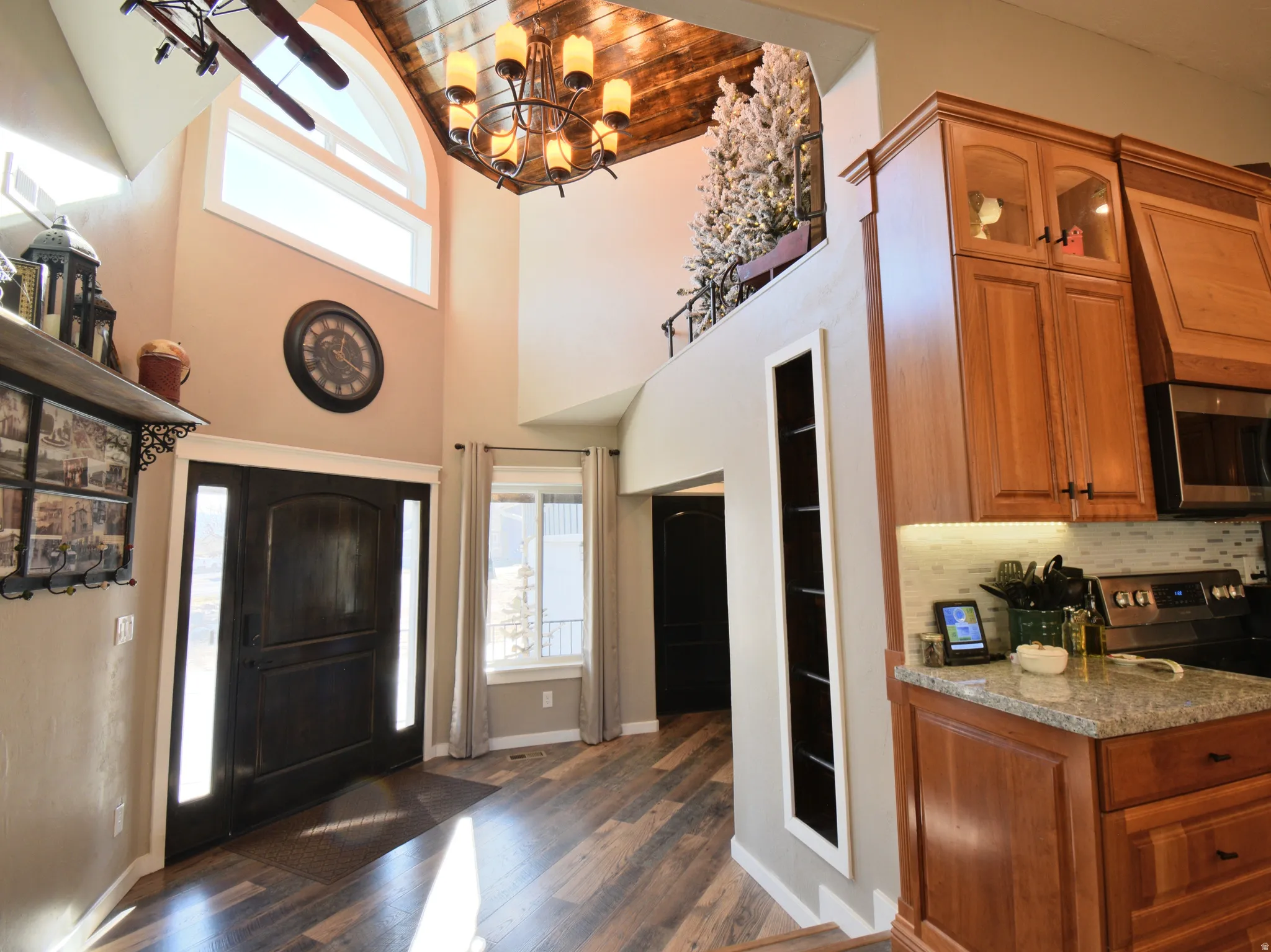 Foyer featuring healthy amount of natural light, wood ceiling, dark wood finished floors, a high ceiling, built in ladder leading to "reading nook", and a chandelier