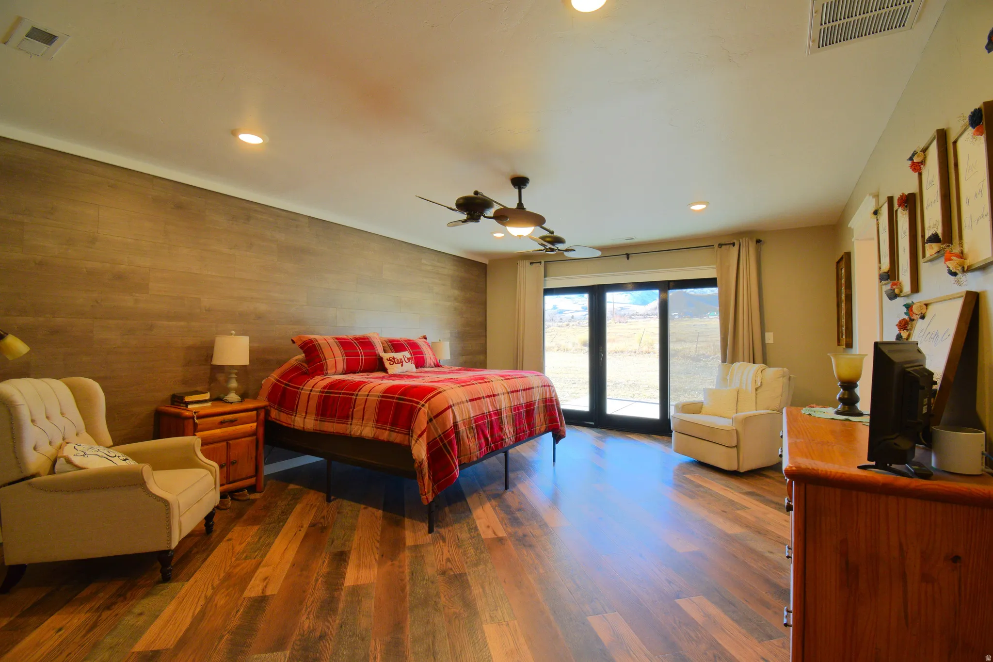 Bedroom with access to exterior- with a covered patio, wood finished floors, recessed lighting, ceiling fan, and an accent wall