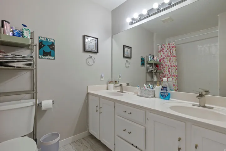 Bathroom with double vanity, a shower with curtain, and light marble finish flooring