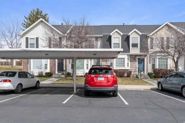 View of front of house with covered and uncovered parking, brick siding, a shingled roof, and entry steps