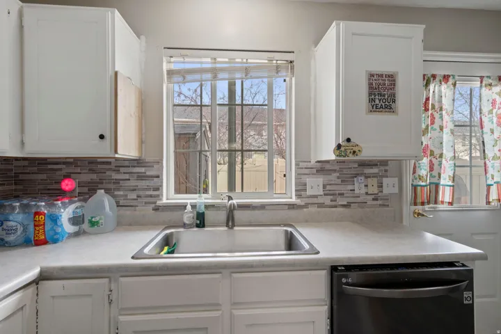 Kitchen with white cabinetry, light countertops, and dishwashing machine