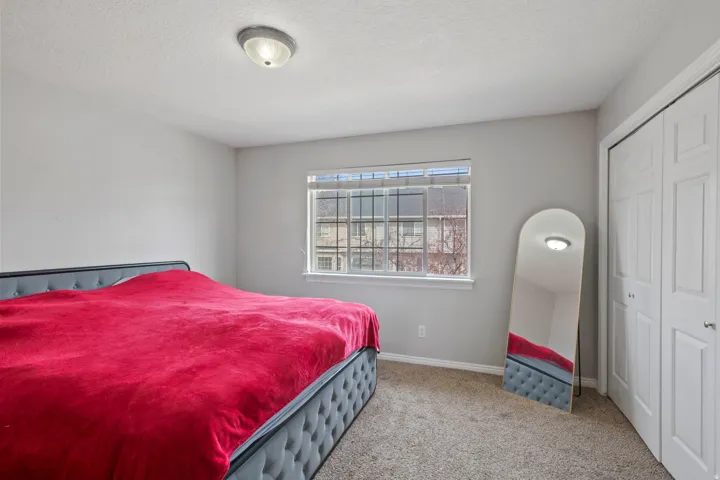 Bedroom with a textured ceiling, light colored carpet, and a closet
