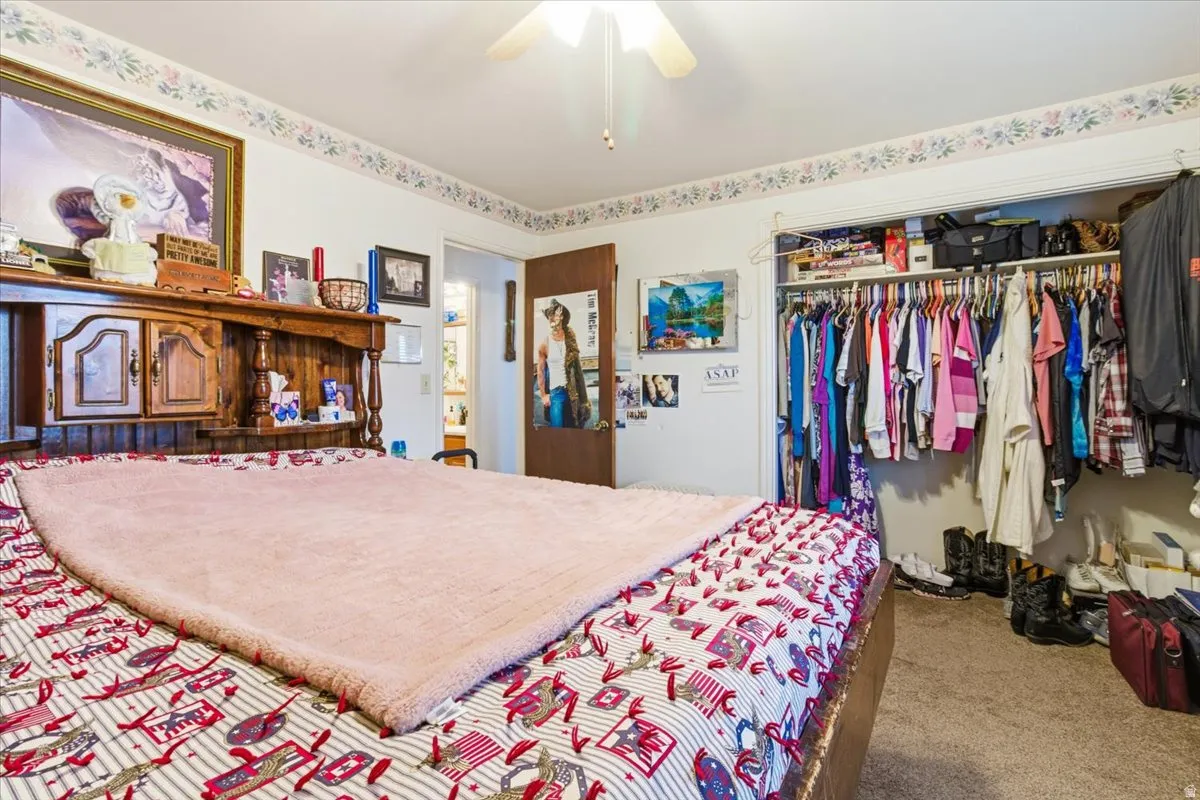 Bedroom featuring light carpet, a ceiling fan, and a closet