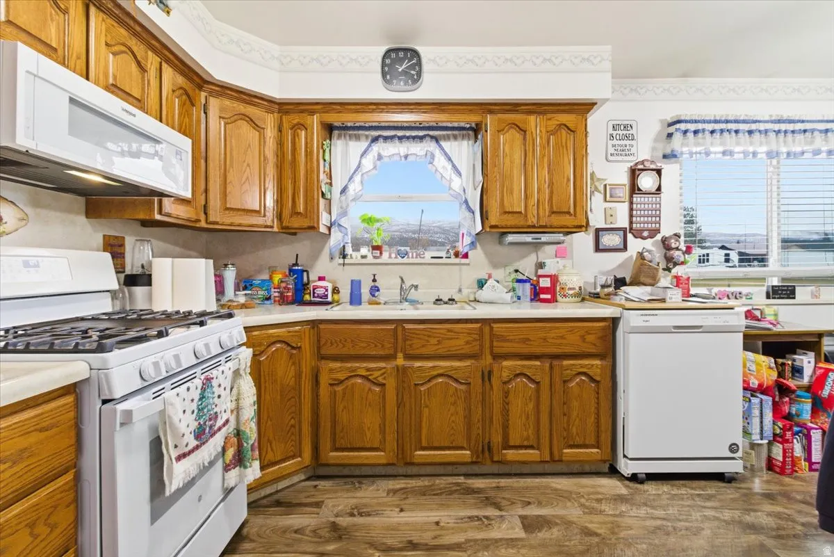 Kitchen featuring white appliances, light countertops, brown cabinets, and dark wood finished floors