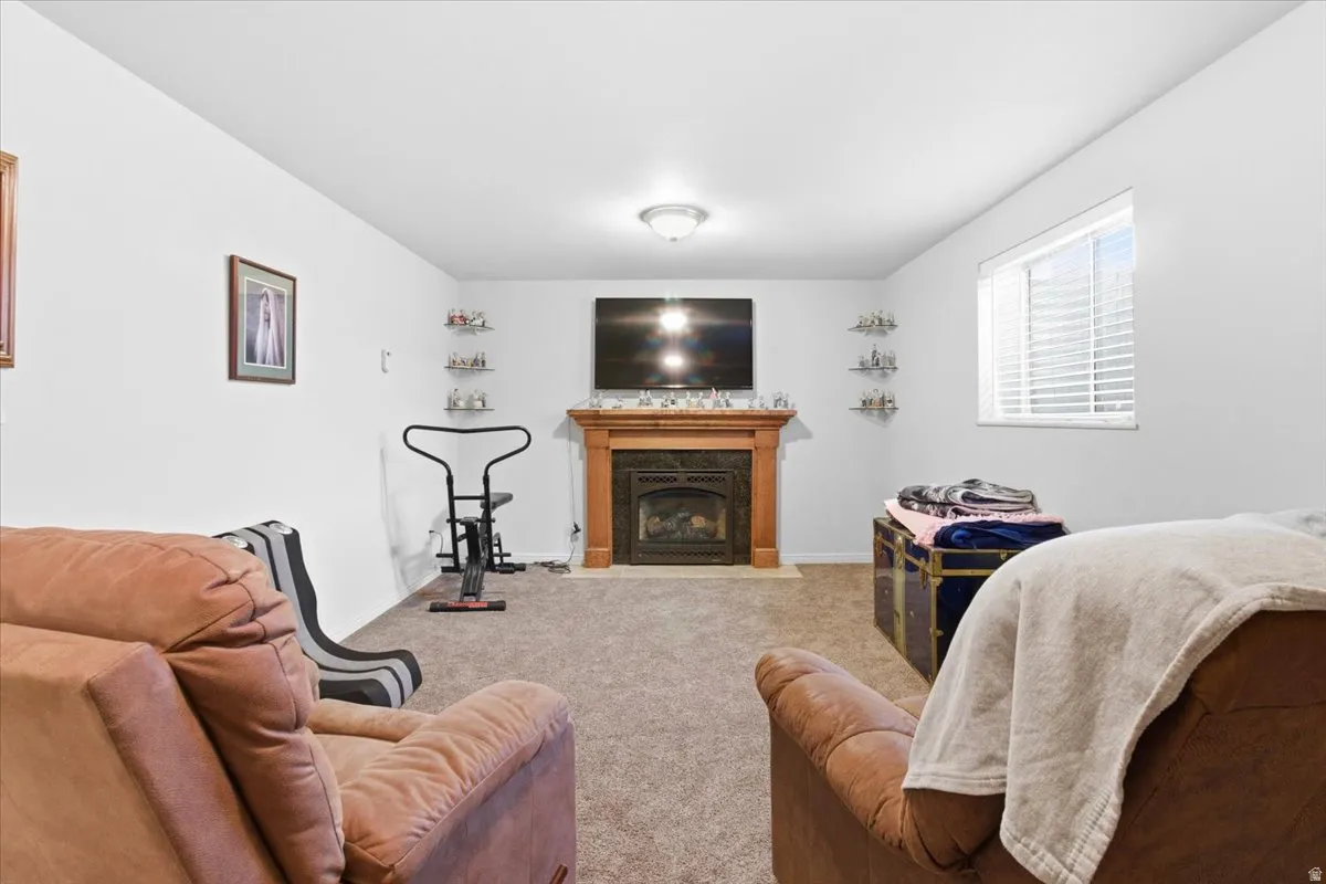 Carpeted living room featuring a fireplace with flush hearth and baseboards