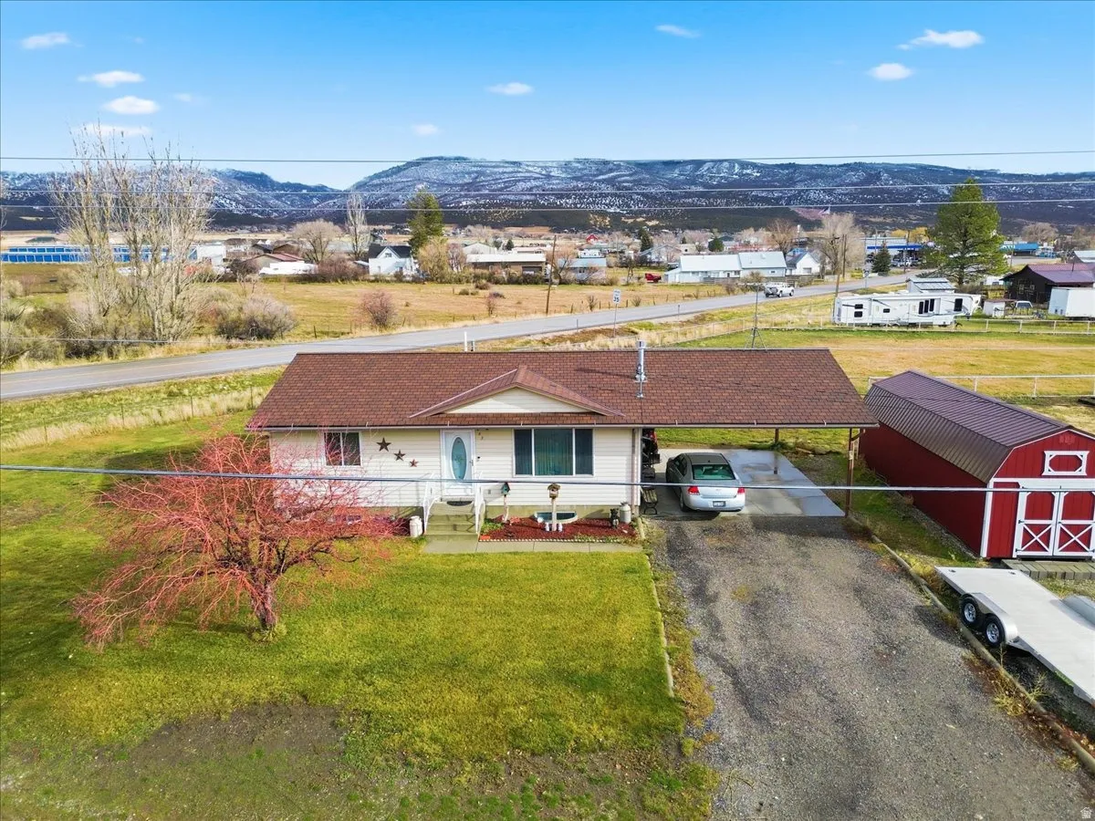 View of front facade featuring a front yard, asphalt driveway, a mountain view, and a storage shed