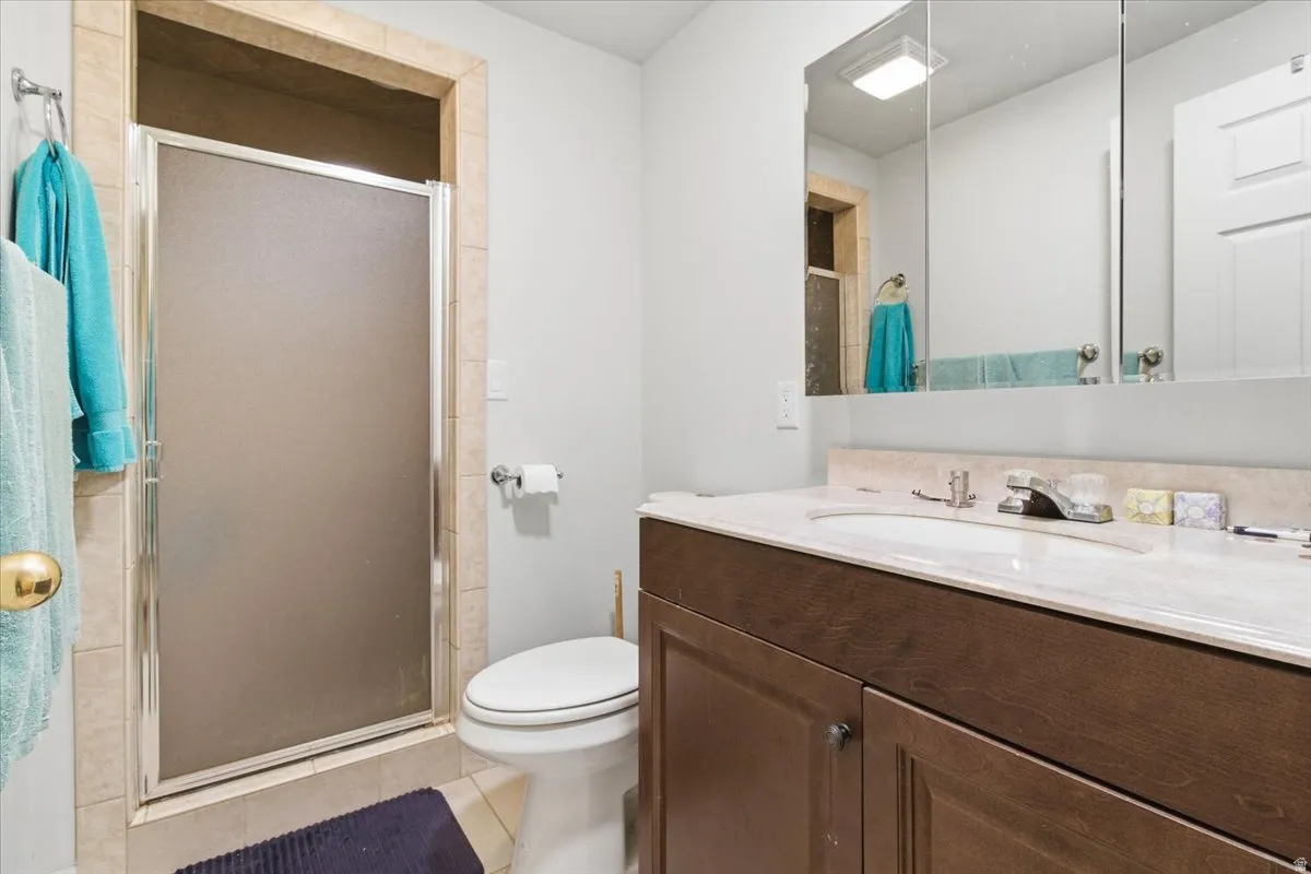 Full bath with vanity, a stall shower, and light tile patterned floors
