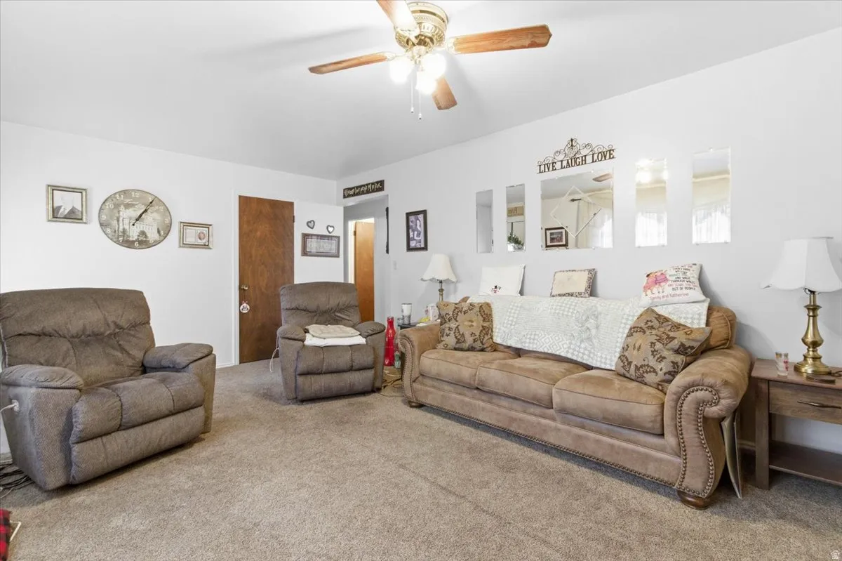 Carpeted living room with a ceiling fan