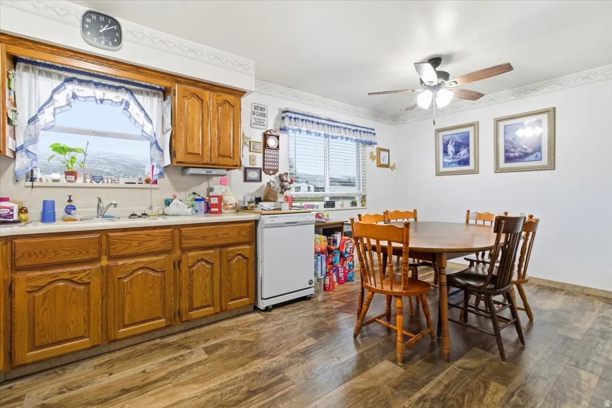 Kitchen with light countertops, brown cabinets, white dishwasher, dark wood-style flooring, and ceiling fan