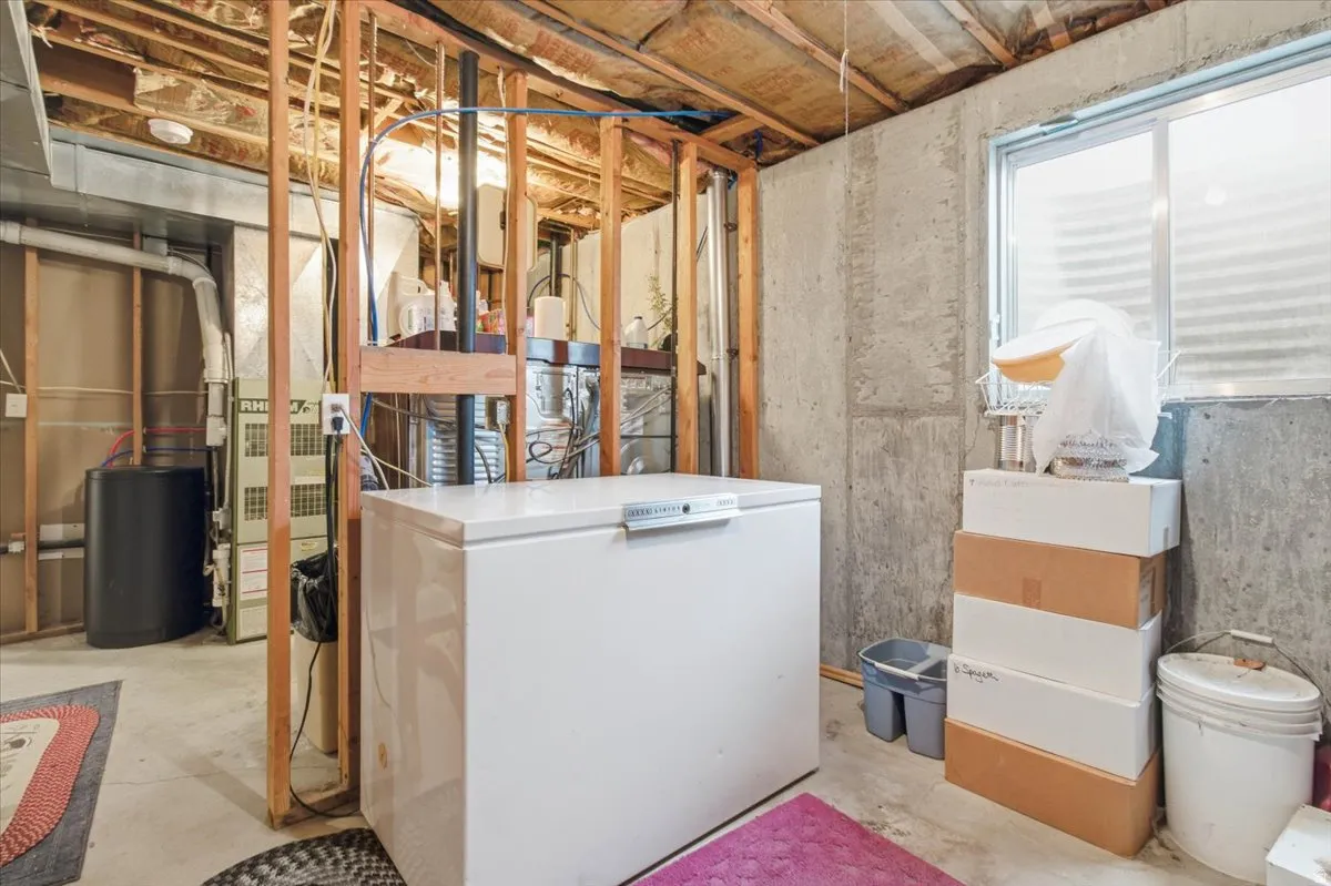 Unfinished basement featuring washer / dryer and heating unit