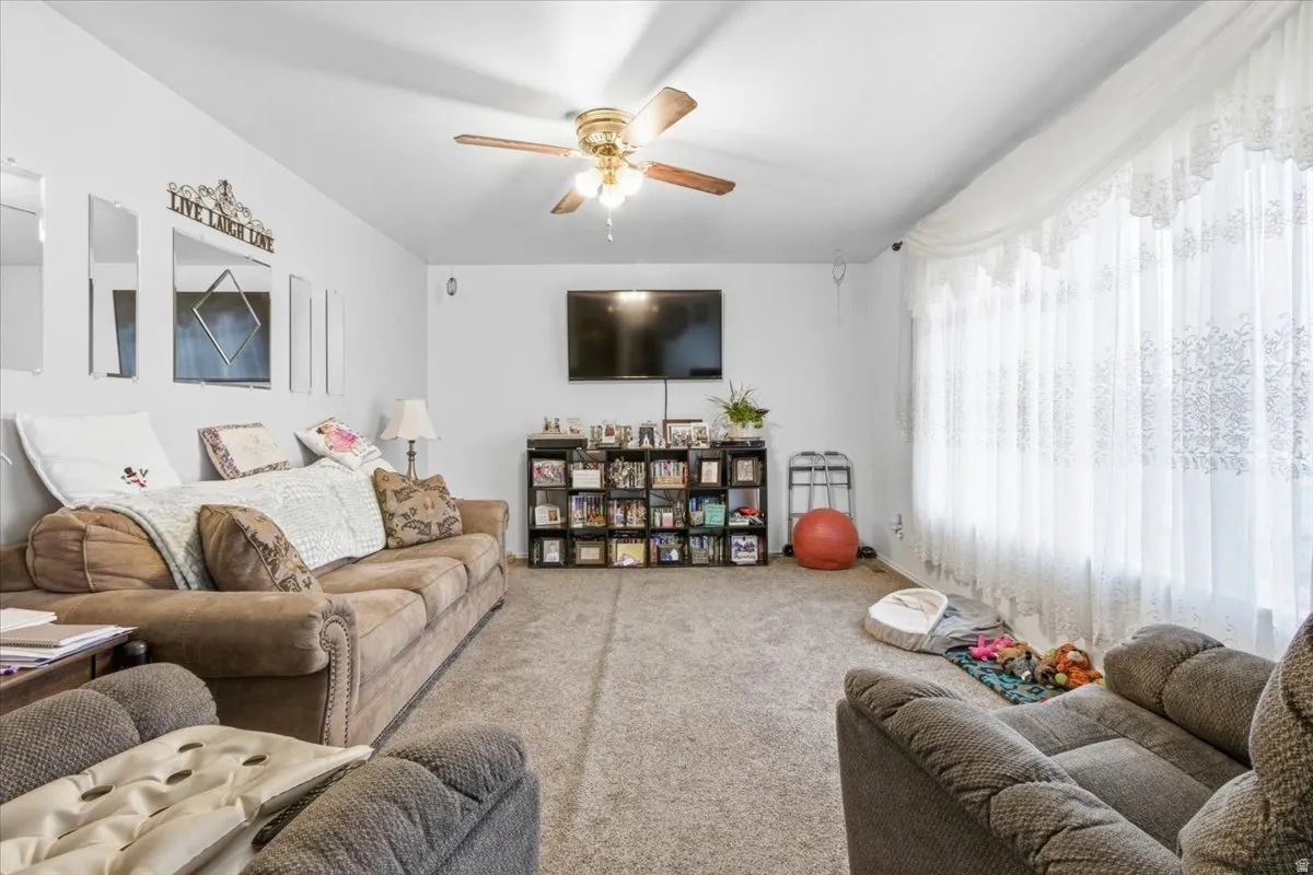 Living room featuring carpet flooring and a ceiling fan