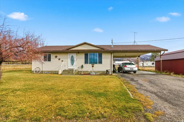 Ranch-style house with driveway, a front lawn, and an attached carport