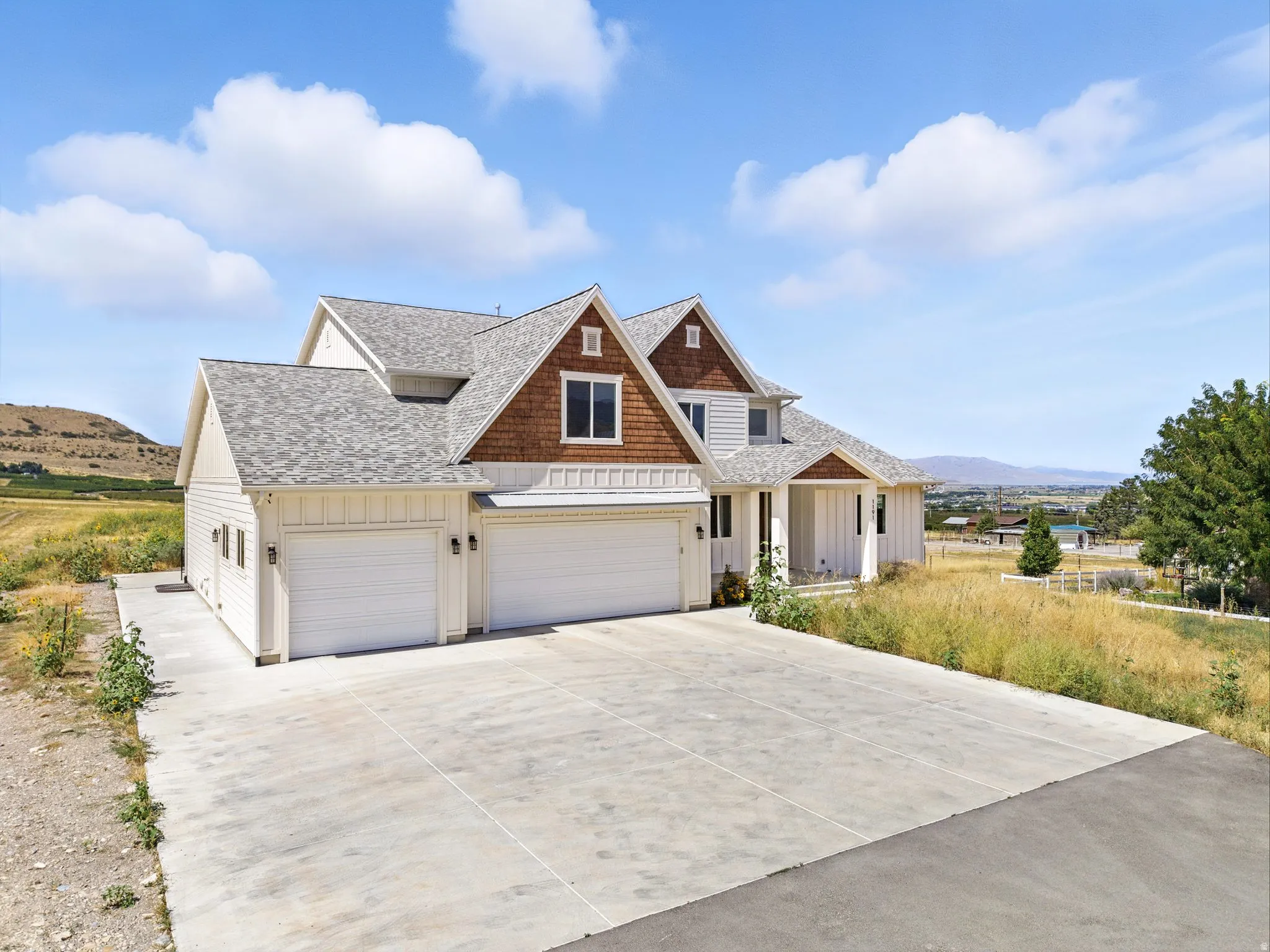 View of front of house featuring board and batten siding, driveway, a shingled roof, and a mountain view
