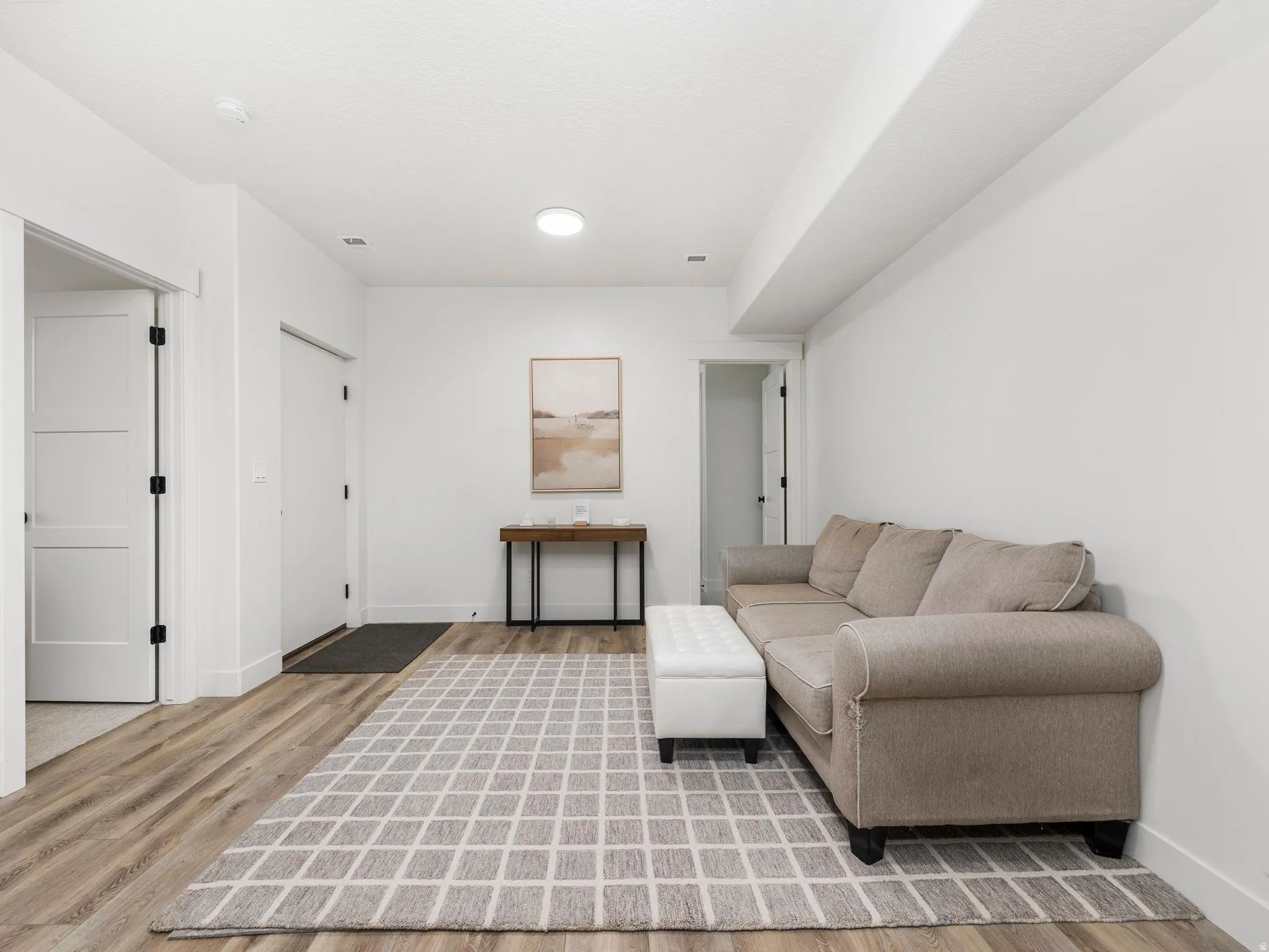 Basement apartment living area featuring light wood-style floors and baseboards