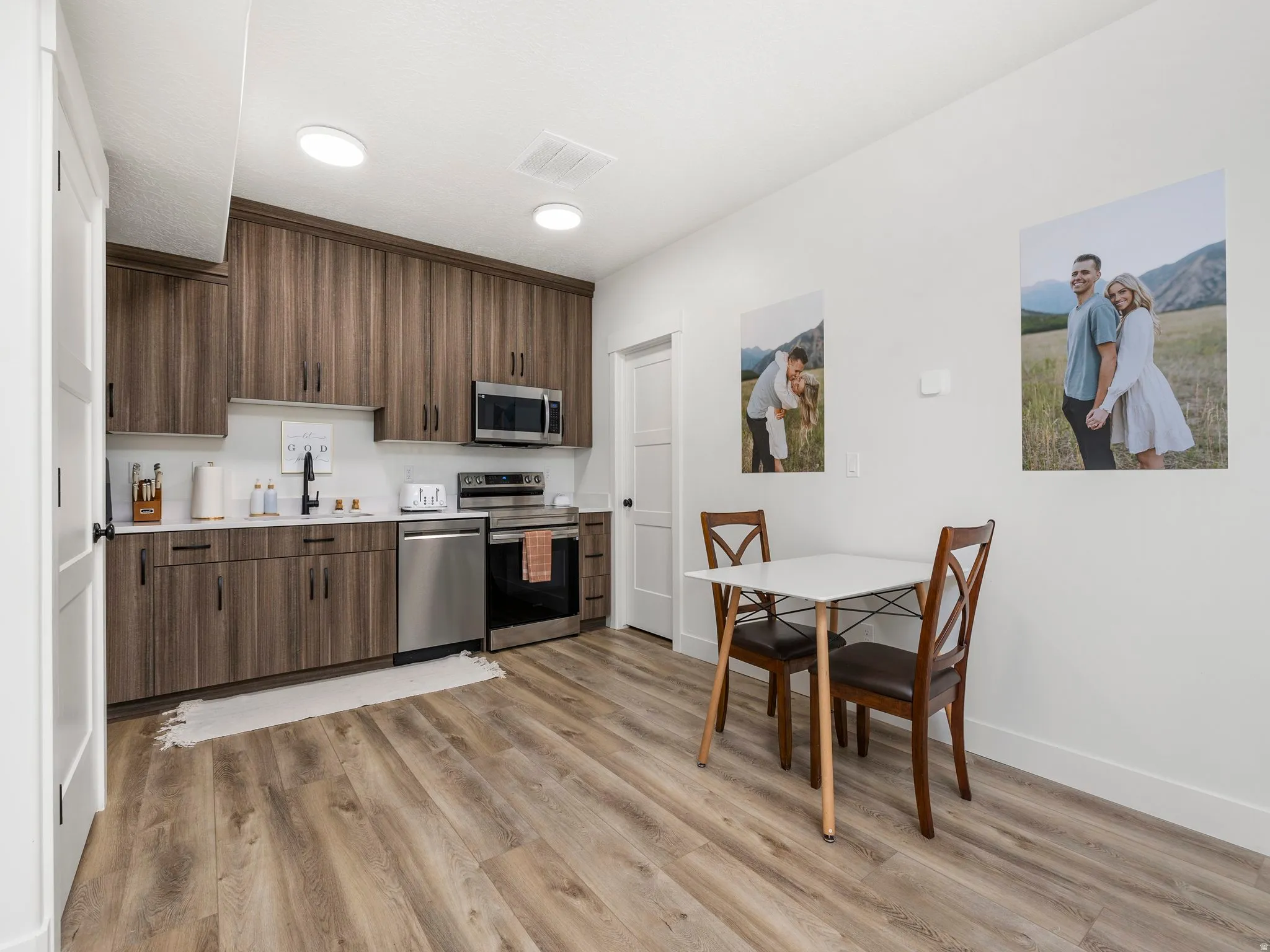 Basement apartment Family room / Kitchen featuring light countertops, appliances with stainless steel finishes, light wood-style flooring, modern cabinets, and recessed dual function lighting