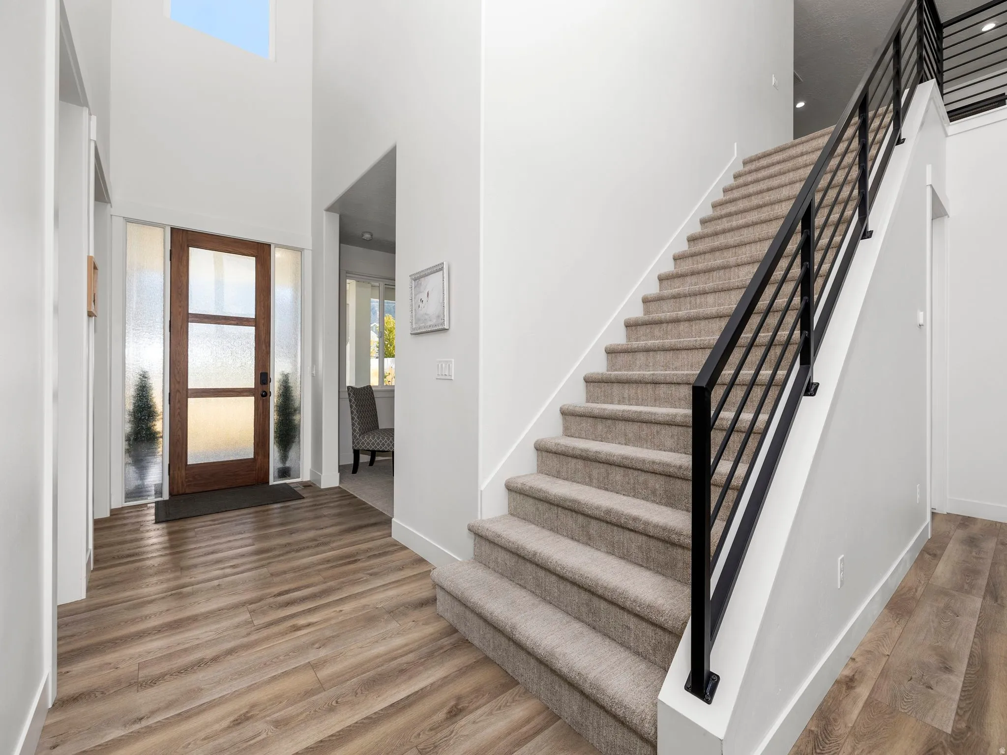 Foyer entrance with healthy amount of natural light, wood finished floors, stairway, and a towering ceiling