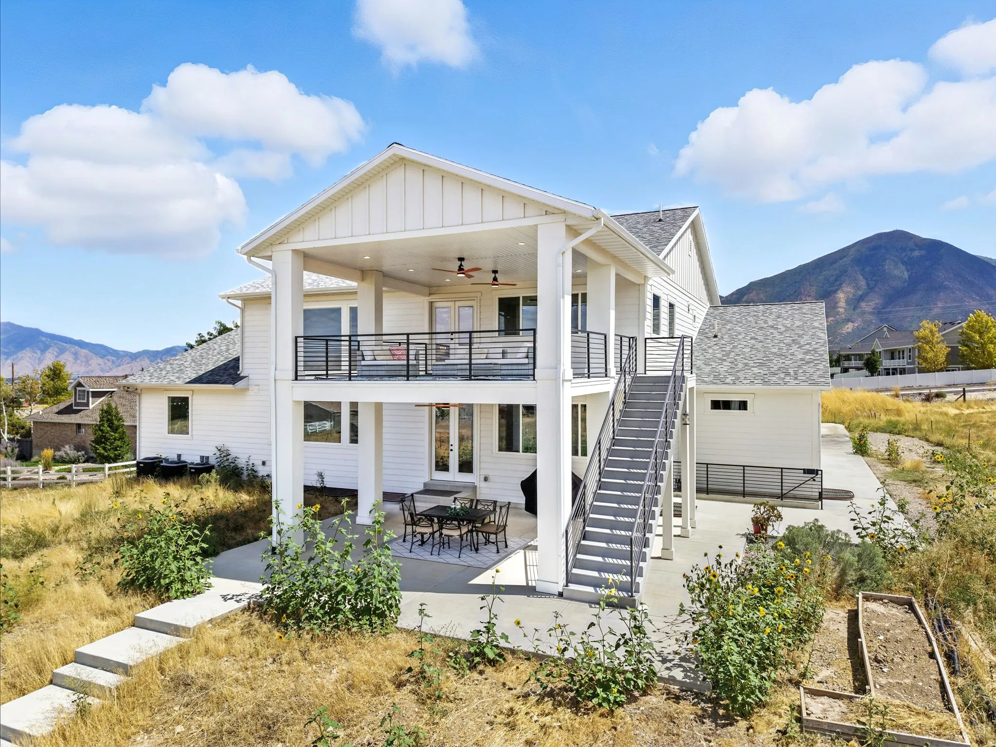 Back of property with a mountain view, a patio, a shingled roof, and a ceiling fan