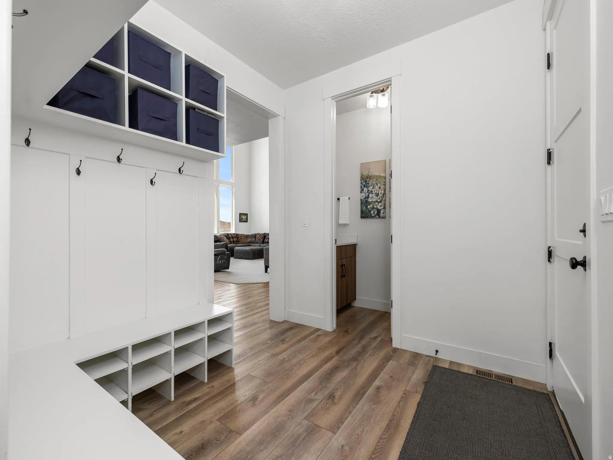 Mudroom featuring custom built-ins, light wood-type flooring and baseboards