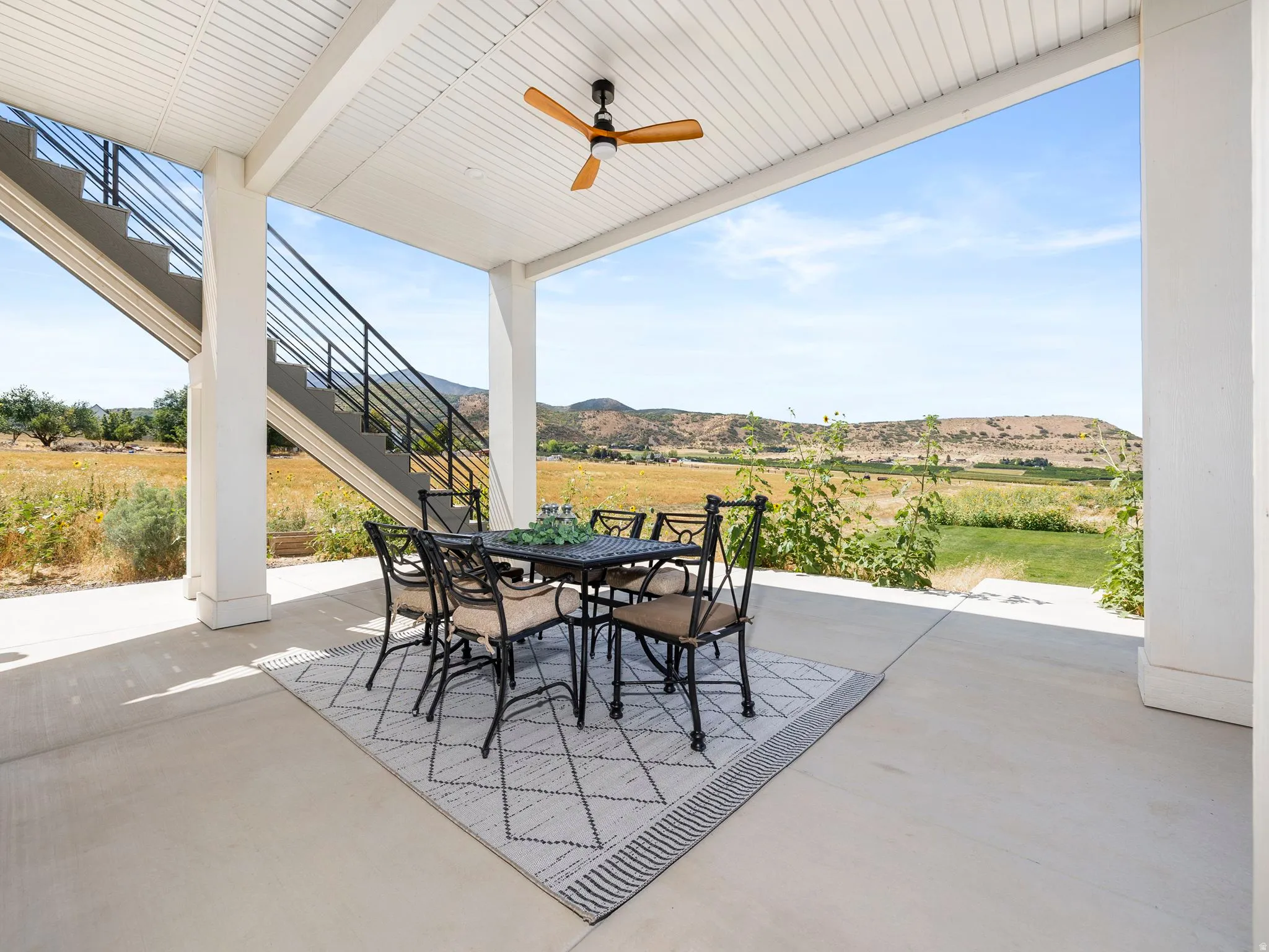 View of patio / terrace with outdoor dining space, stairs, a ceiling fan, and a mountain view