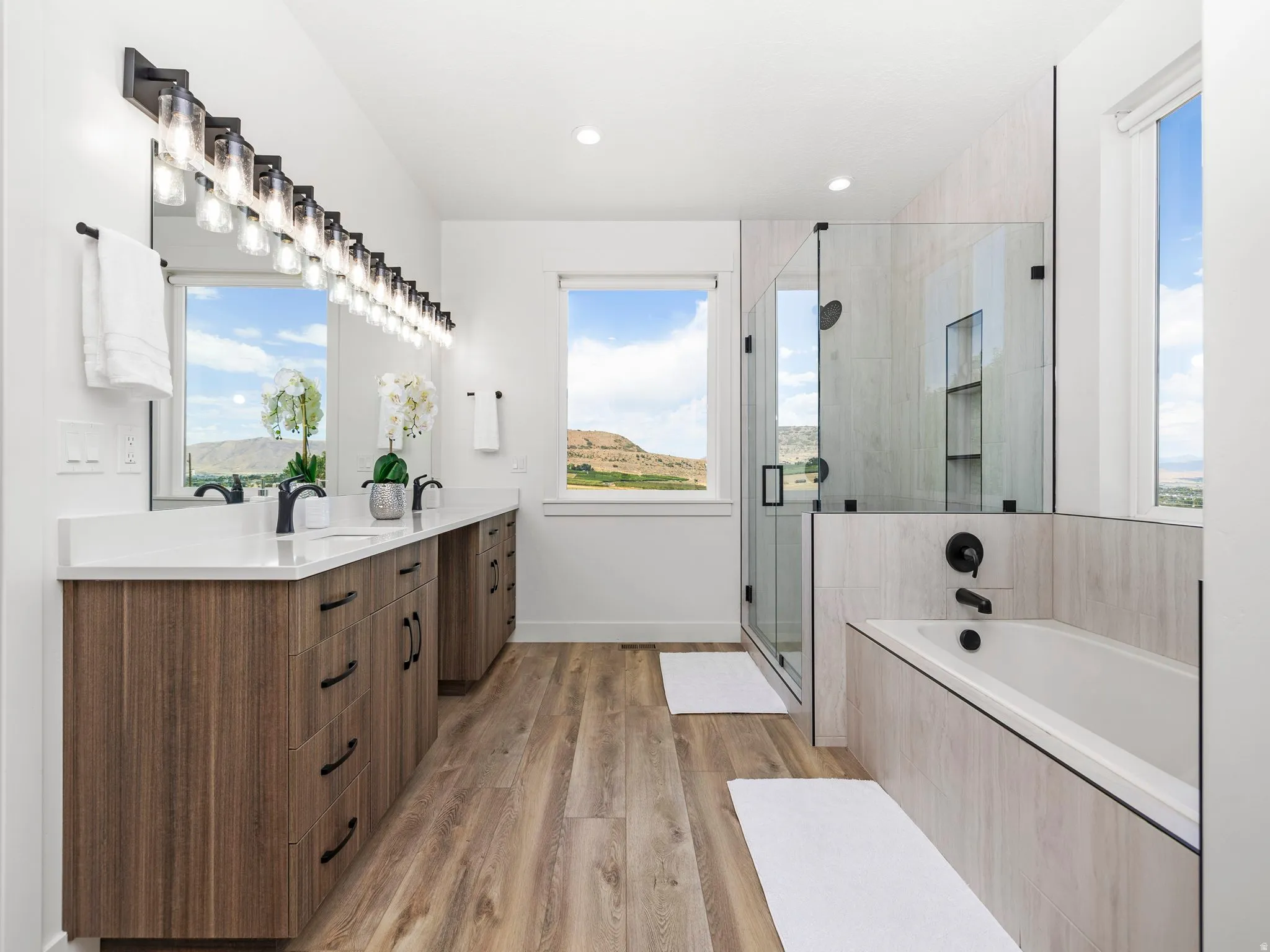 Owners suite full bath featuring double vanity, a stall shower, a bath, healthy amount of natural light, and recessed lighting
