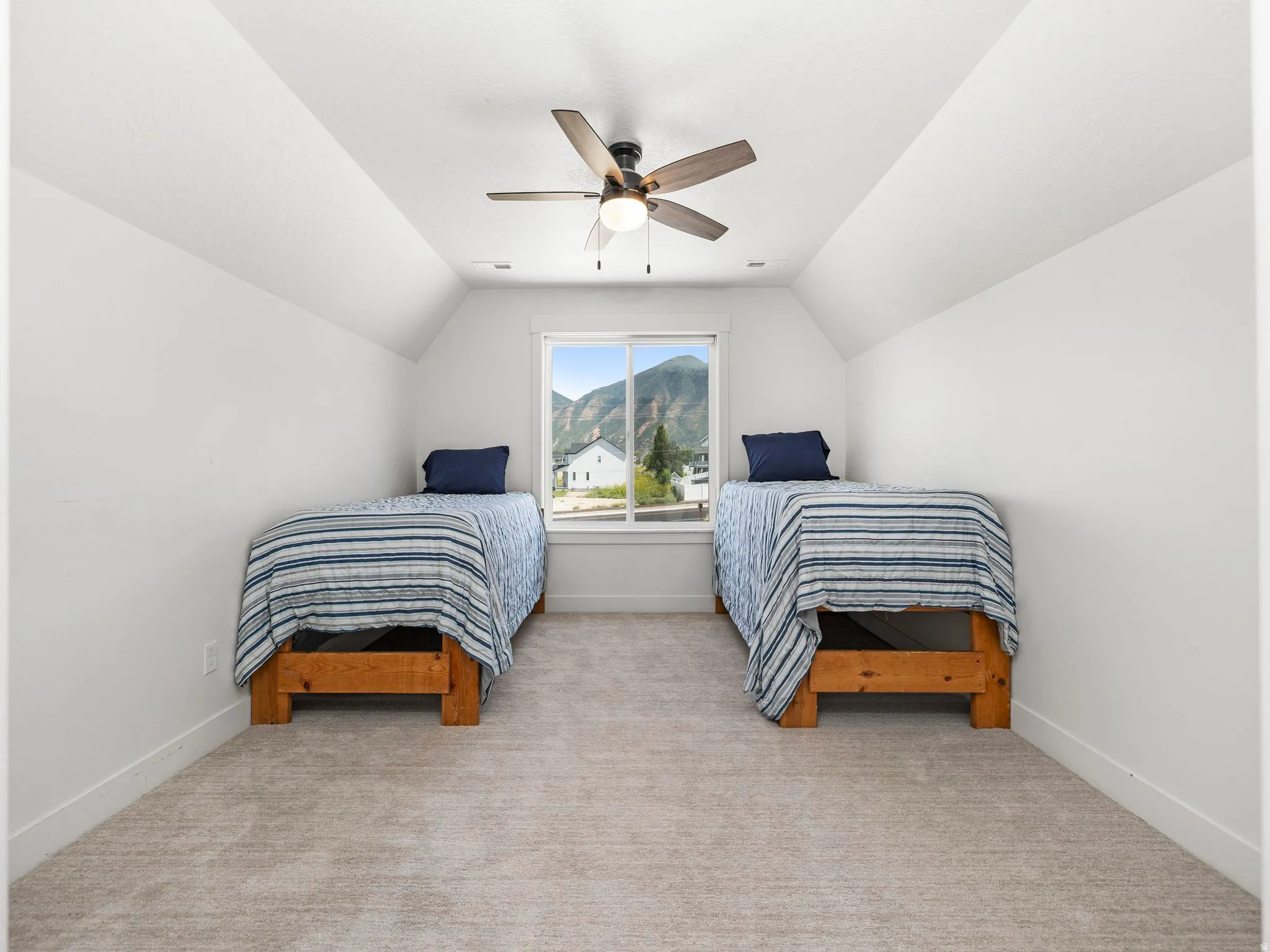 Bedroom with light colored carpet, a ceiling fan, vaulted ceiling, and a mountain view
