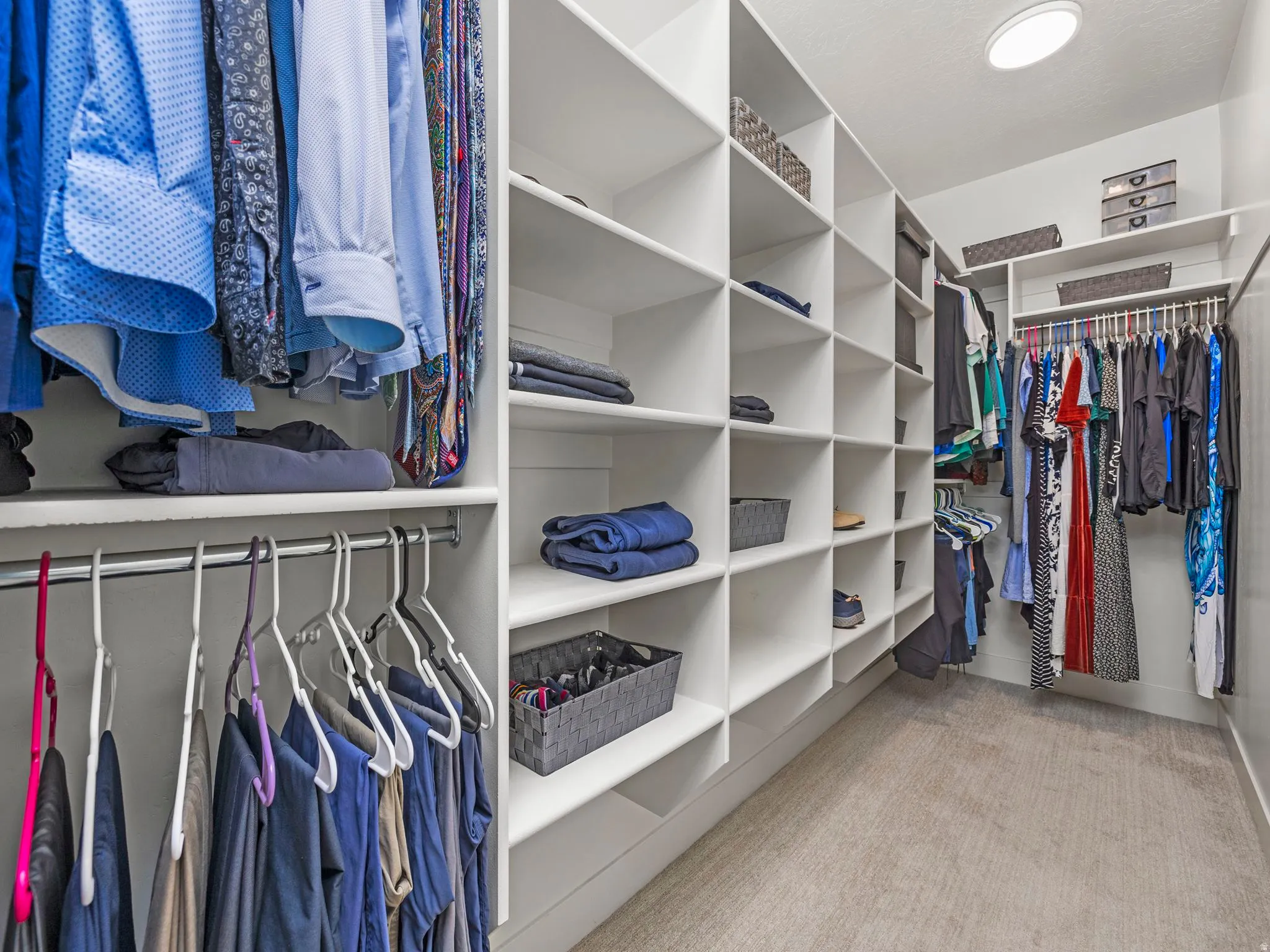 Owners suite spacious walk-in closet featuring custom shelving light carpet and dual feature led lights