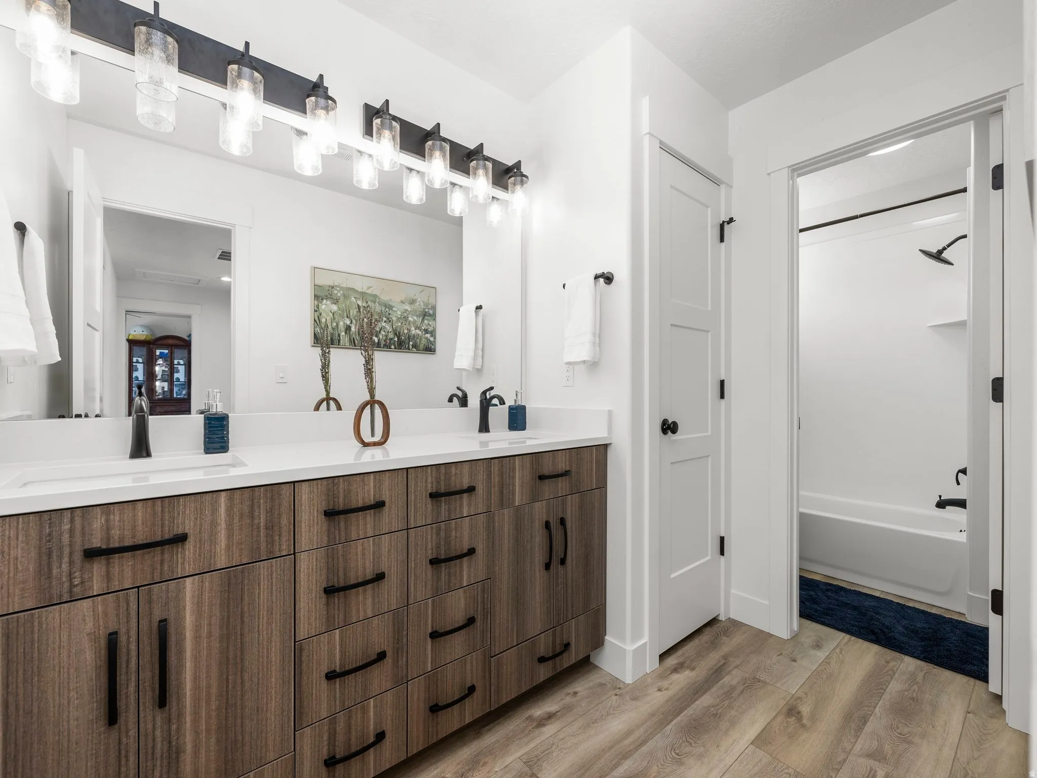 Bathroom featuring double vanity, light wood finished floors, and tub / shower combination