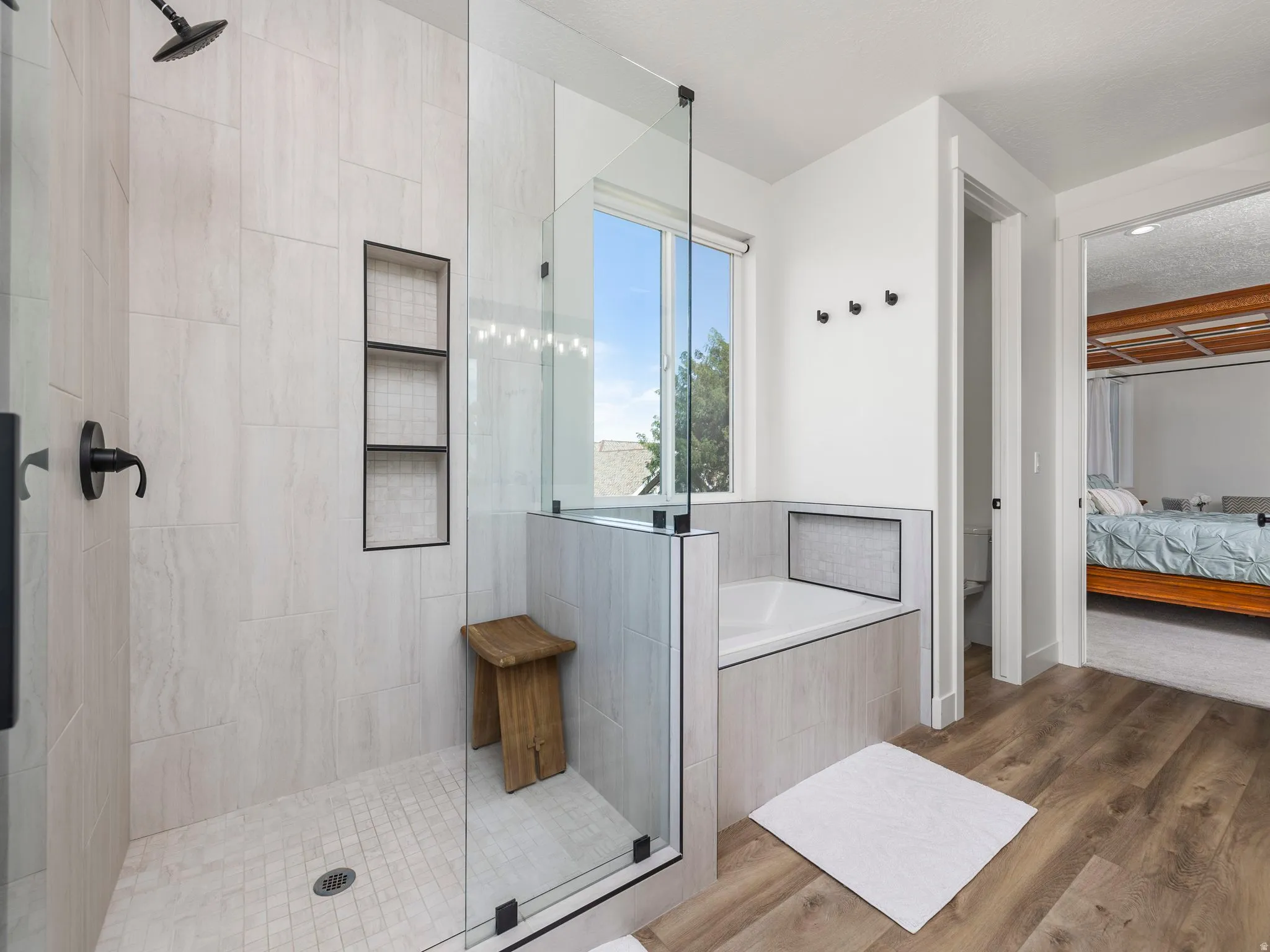 Owners suite full bath featuring ensuite bath, wood finished floors, a shower stall, and a garden tub