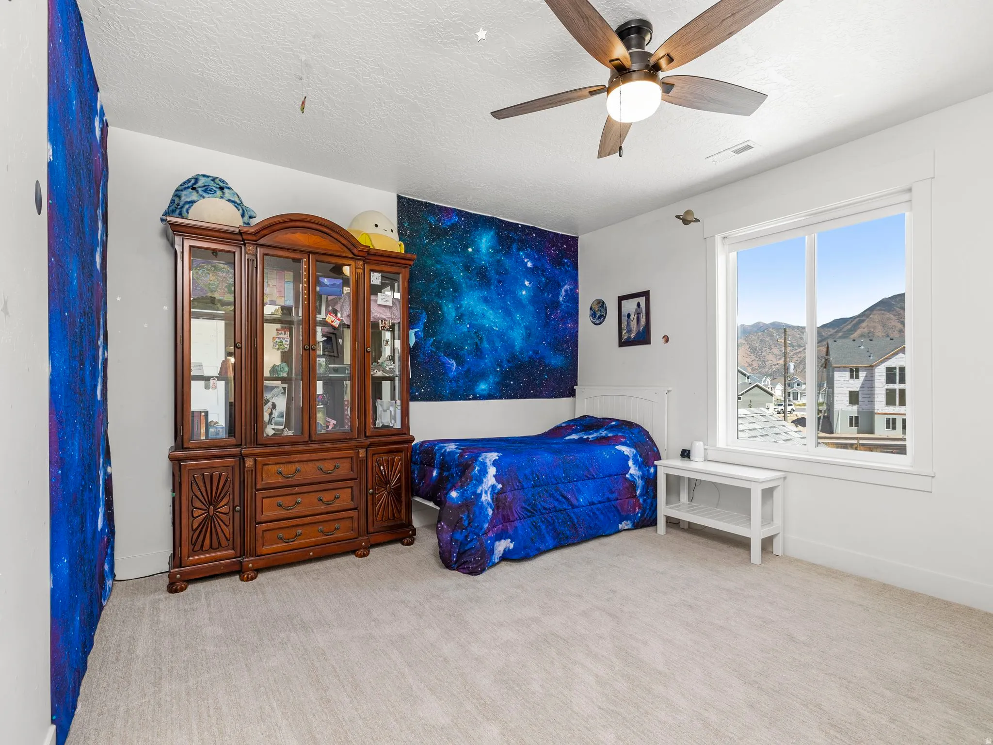 Bedroom with a ceiling fan, light colored carpet, and a textured ceiling