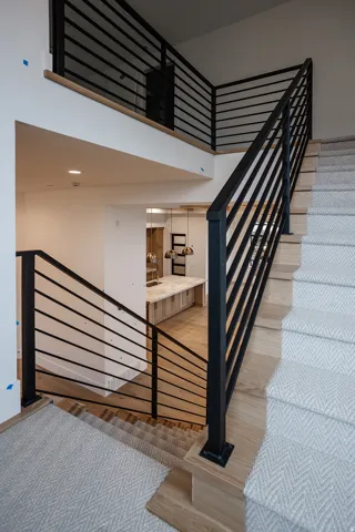 Stairs with a towering ceiling and wood finished floors