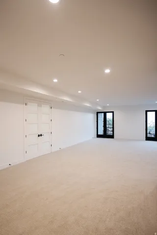 Basement with recessed lighting, light carpet, and french doors