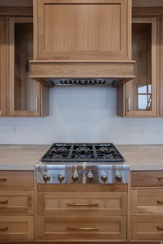 Kitchen featuring premium range hood, stainless steel gas cooktop, and light countertops