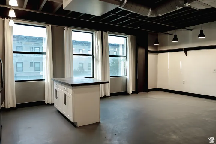 Kitchen featuring white cabinets, finished concrete floors, and dark countertops