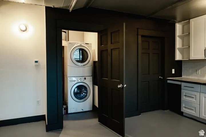 Washroom with stacked washer / dryer and finished concrete flooring