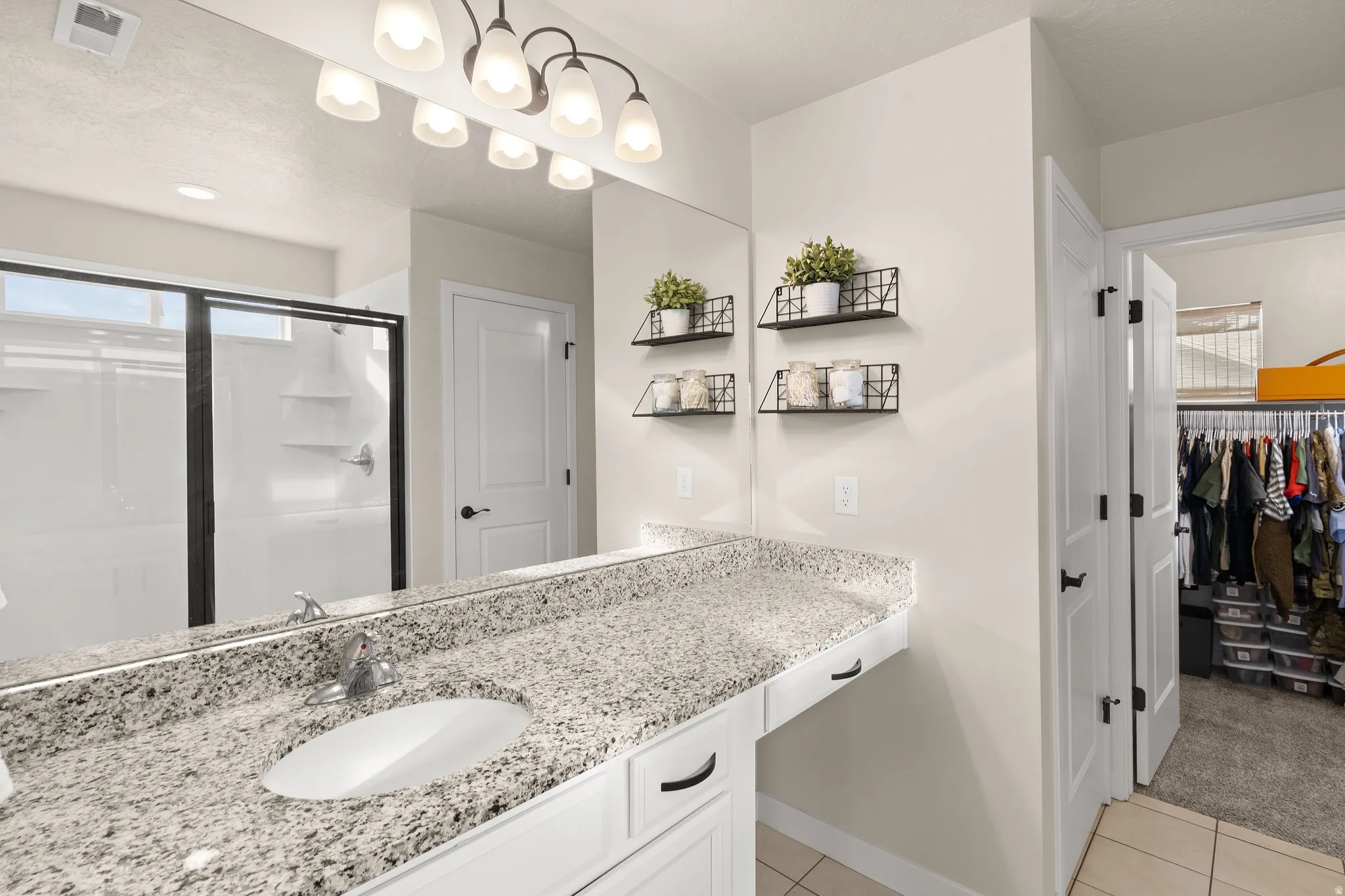 Bathroom with vanity, a shower stall, light tile patterned floors, a spacious closet, and light colored carpet