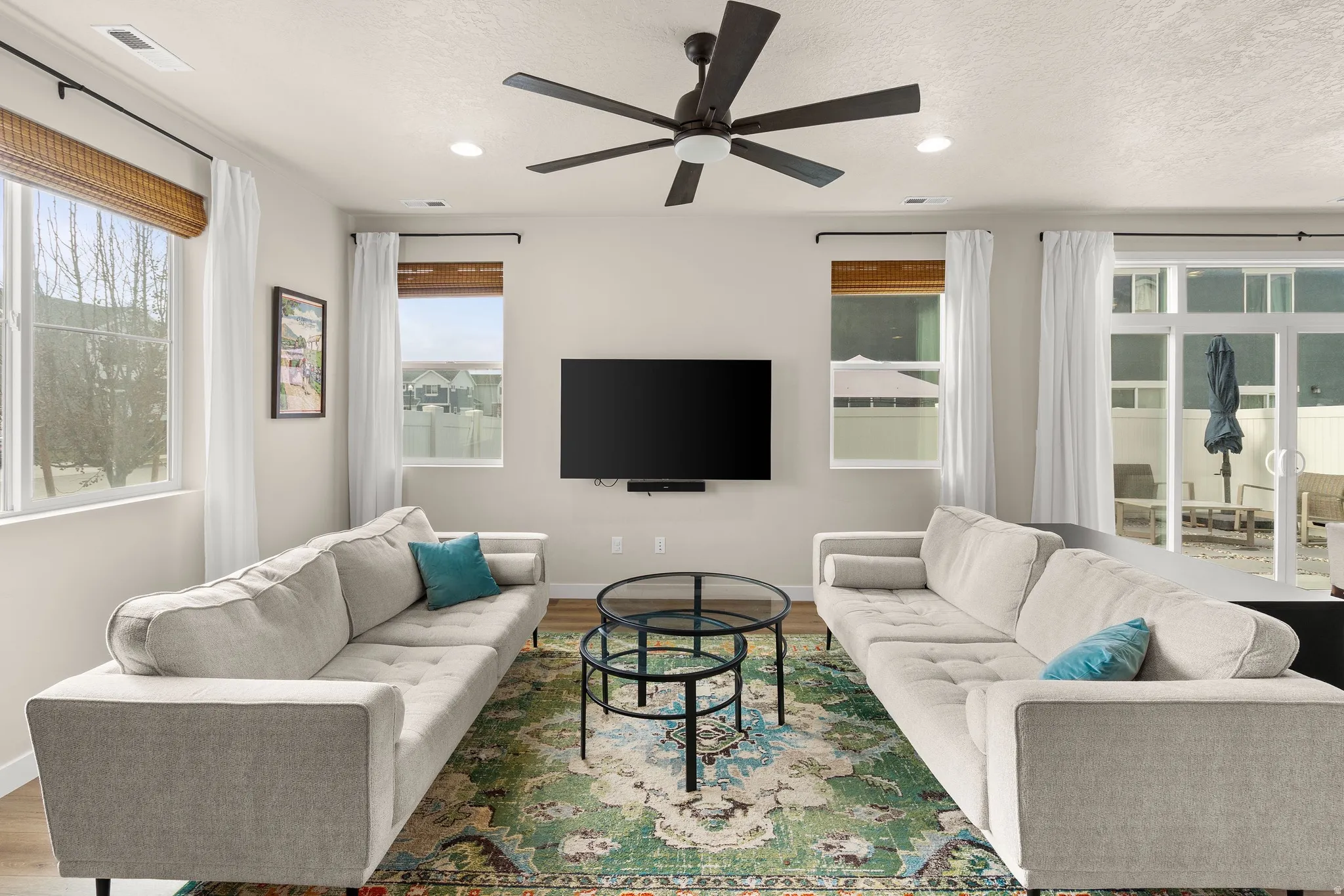 Living room featuring wood finished floors, a ceiling fan, and a textured ceiling