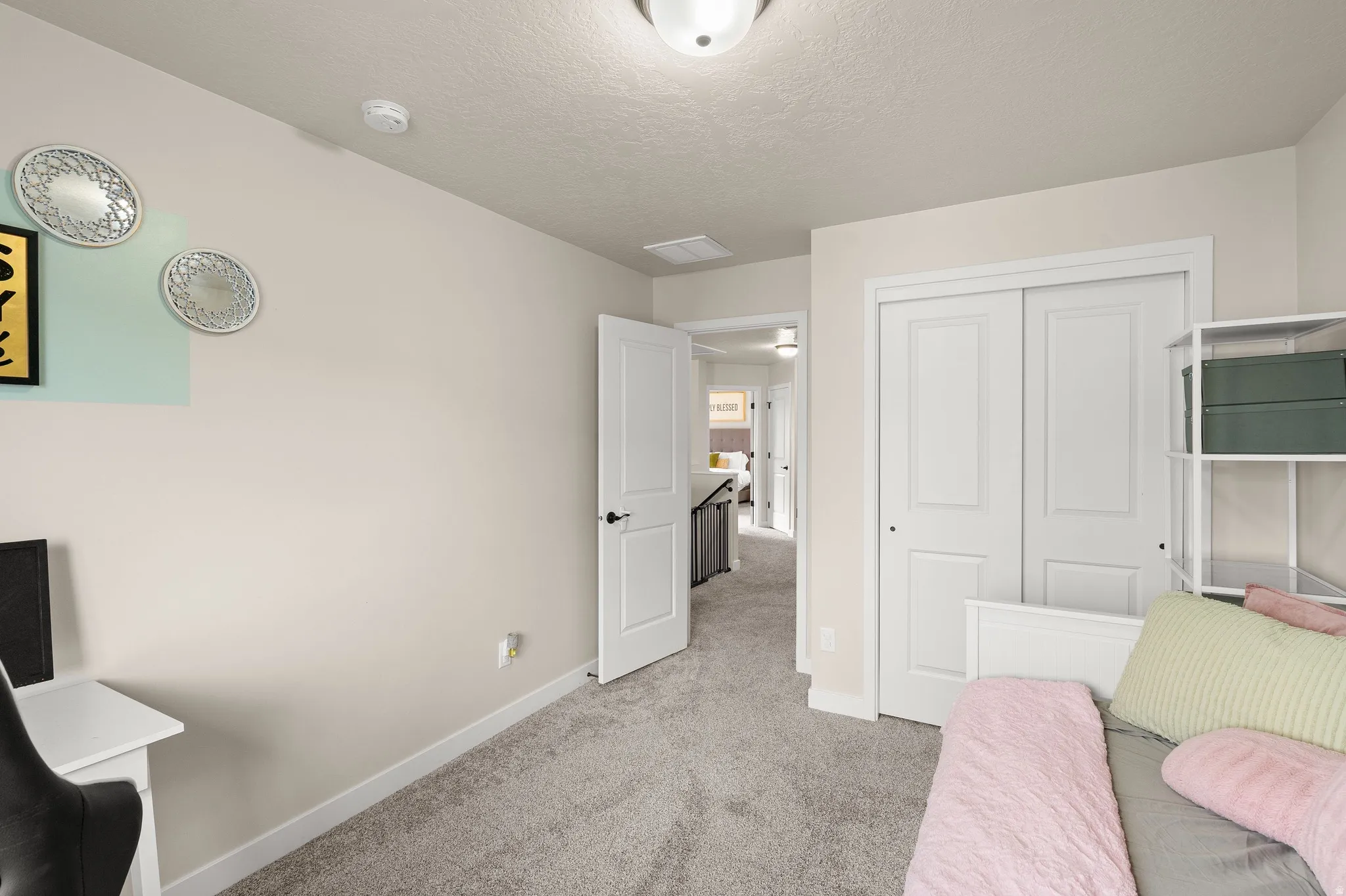 Bedroom featuring light colored carpet, a textured ceiling, and a closet