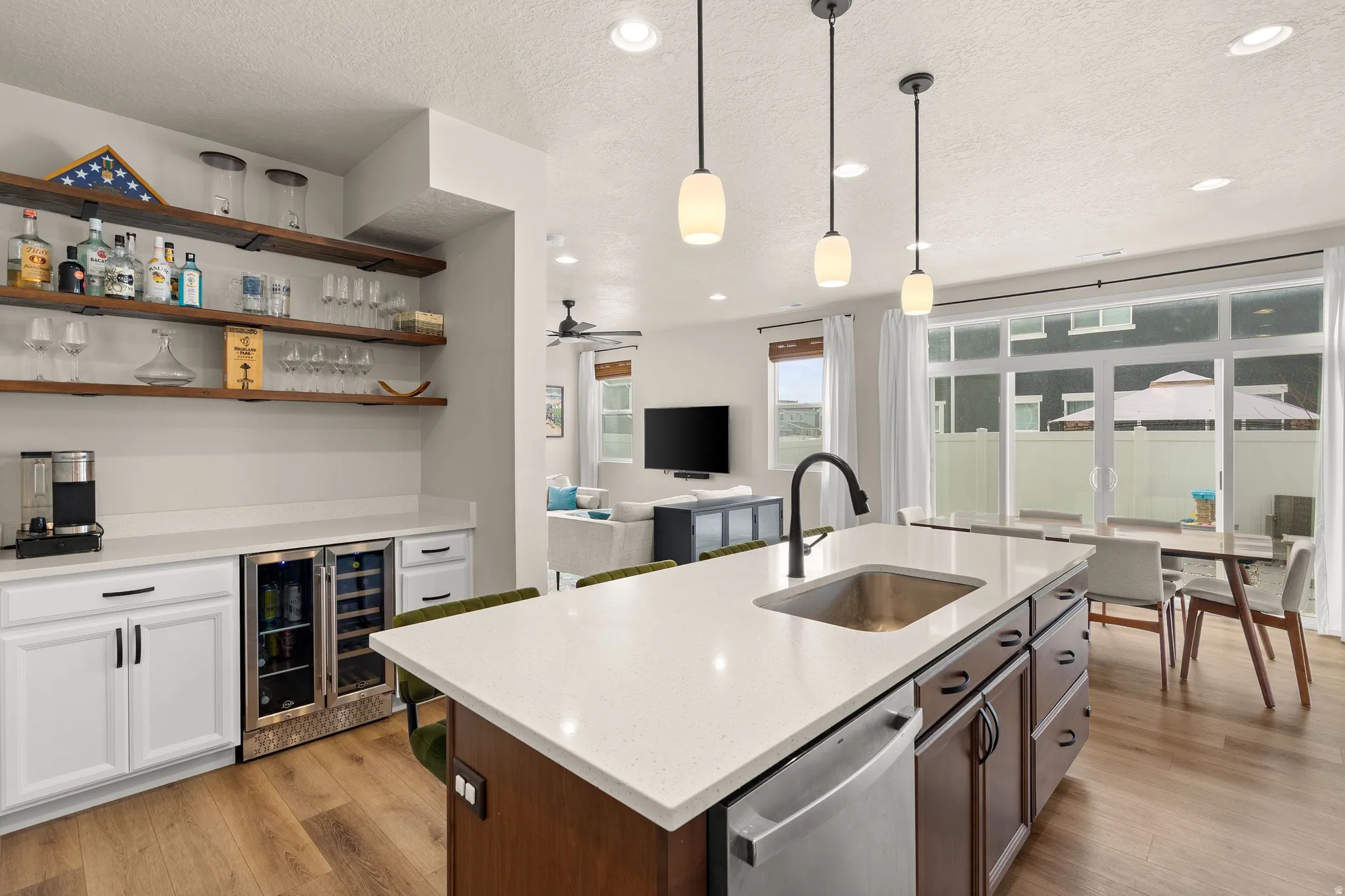 Kitchen featuring open shelves, a textured ceiling, light stone counters, white cabinets, and beverage cooler