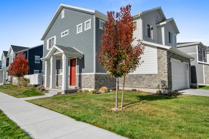 View of front of home featuring stone siding, a front lawn, and an attached garage