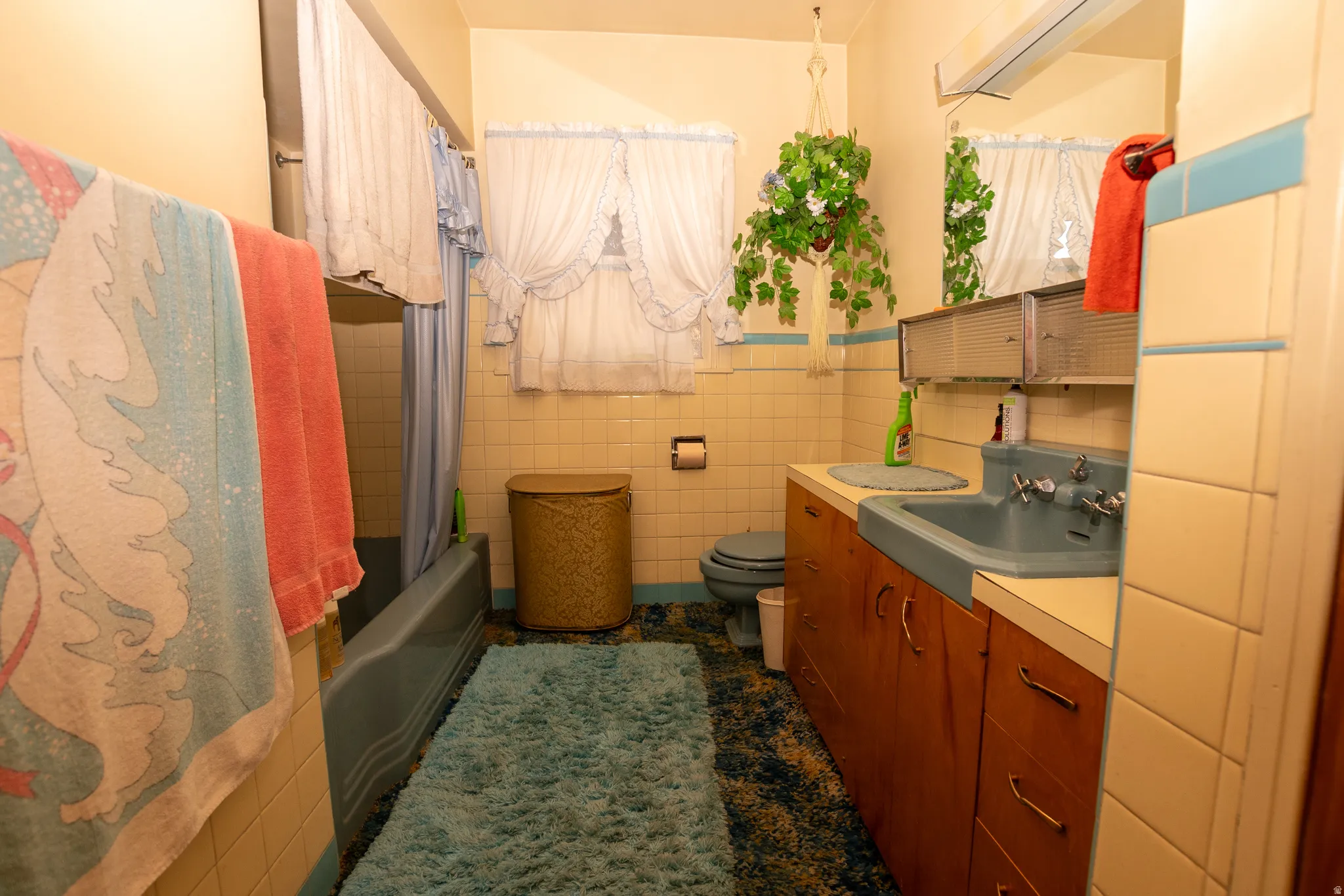 Bathroom featuring tile walls, vanity, shower / tub combo with curtain, and a wainscoted wall