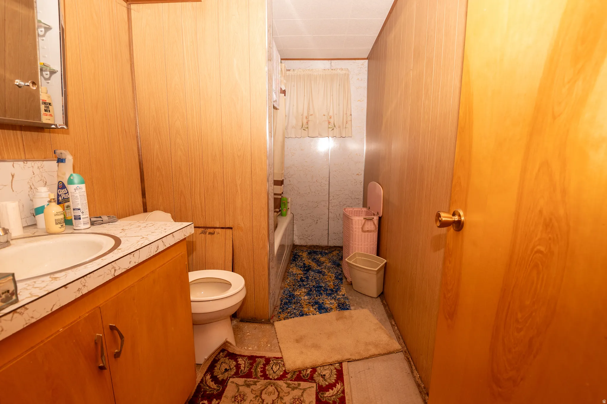 Full bath with wood walls, vanity, and shower / bath combination