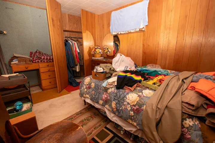 Bedroom featuring a closet and wood walls
