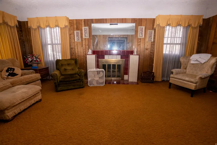 Sitting room with a fireplace, carpet flooring, a textured ceiling, and wooden walls