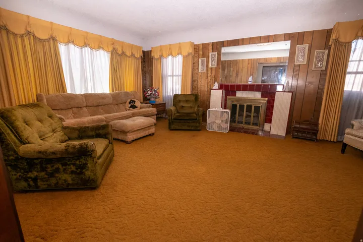Carpeted living room with a tiled fireplace, a textured ceiling, and wood walls