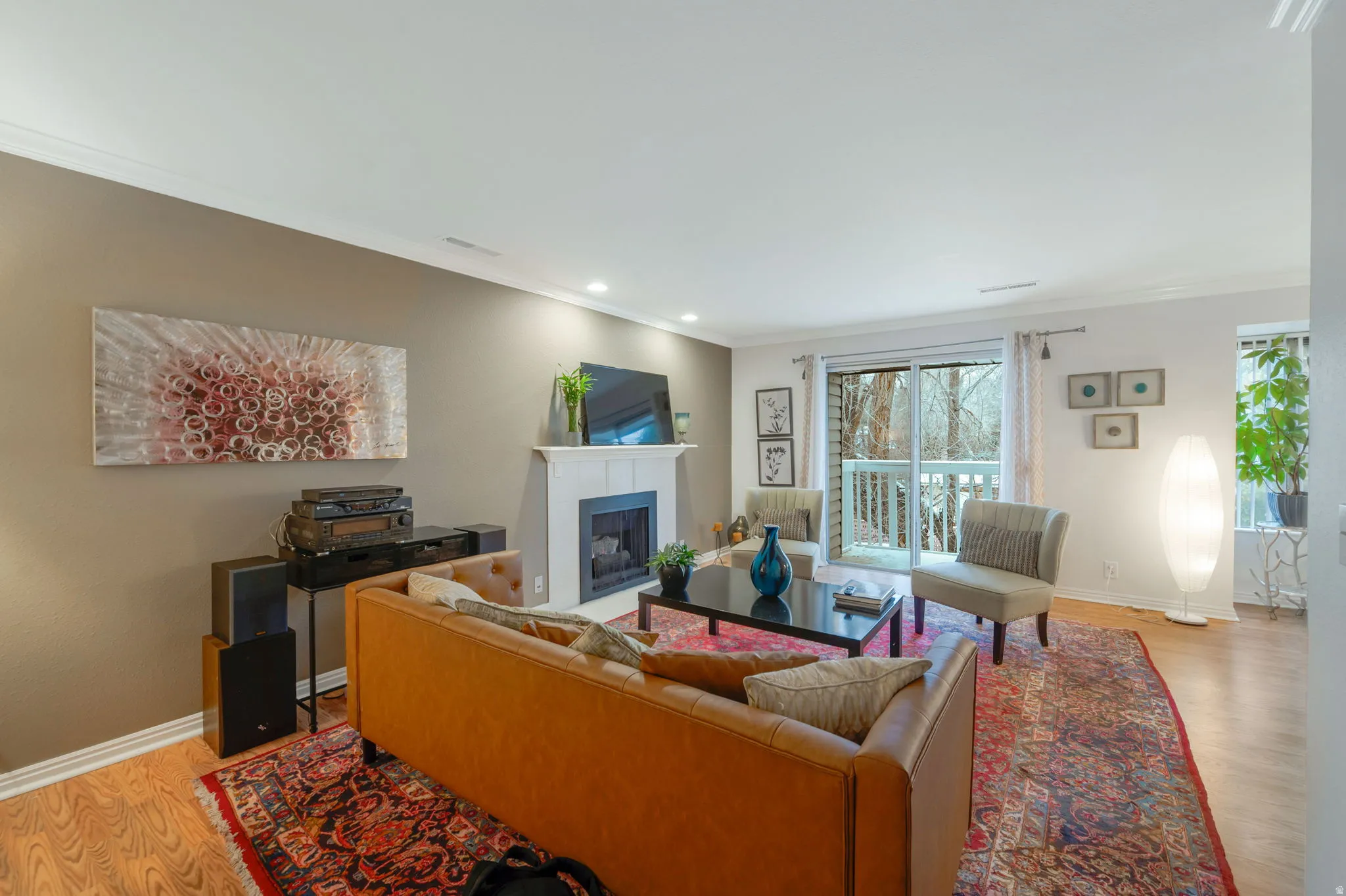 Living room with light wood-type flooring, a fireplace, ornamental molding, and recessed lighting