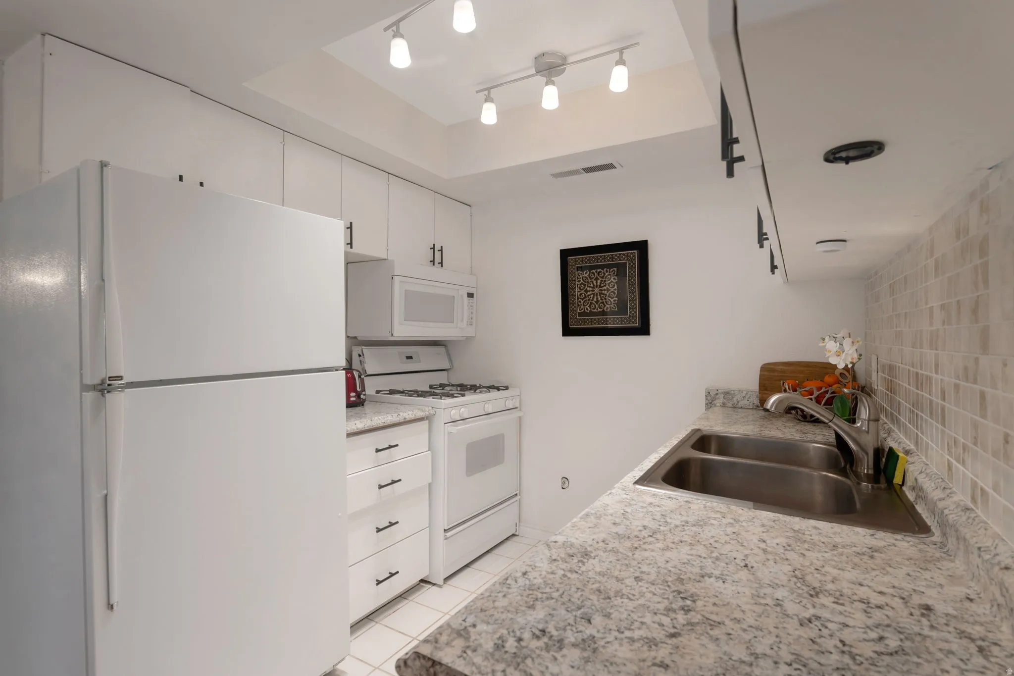 Kitchen with white appliances, white cabinetry, light countertops, and light tile patterned floors