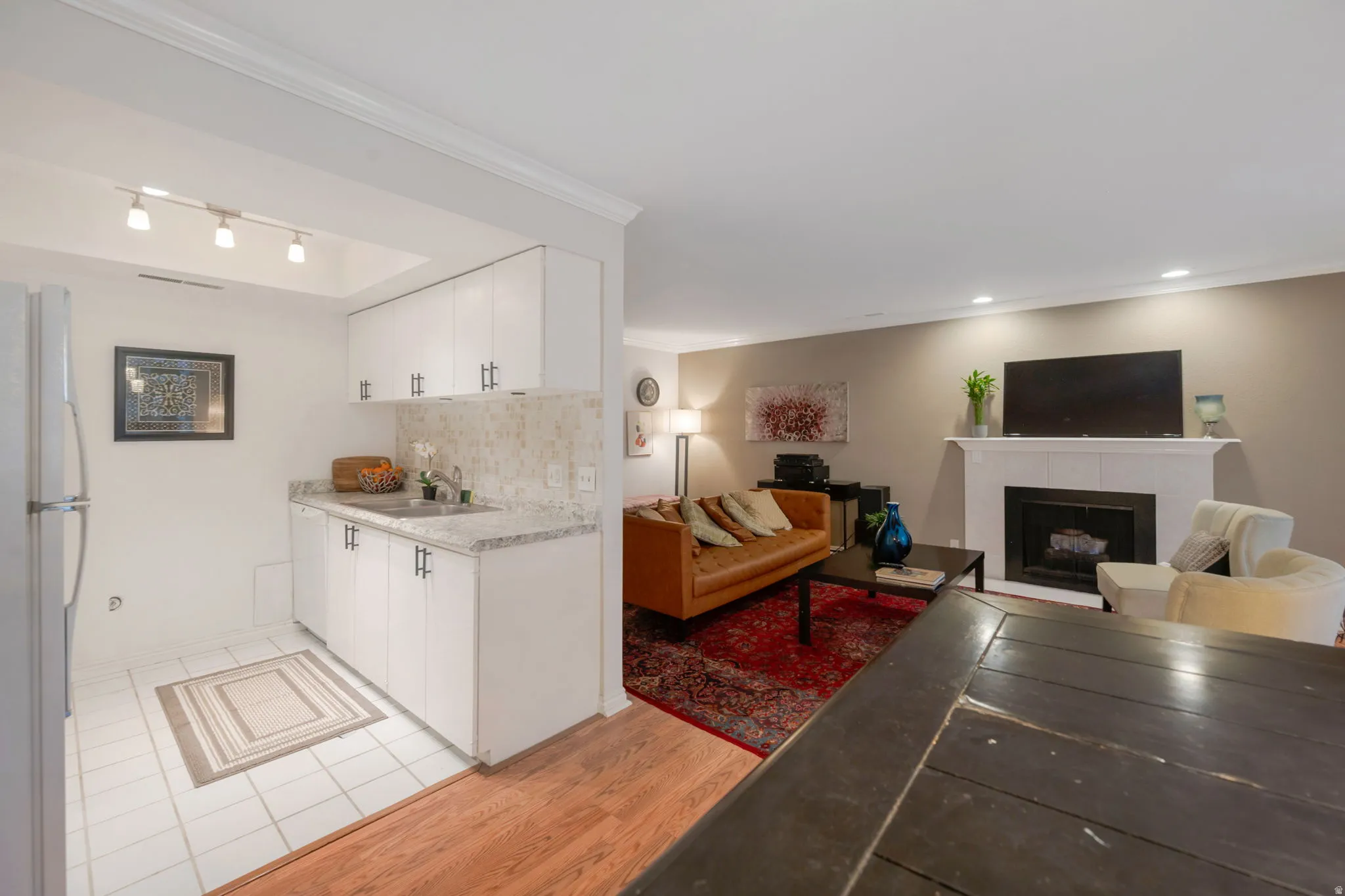 Kitchen with white cabinets, open floor plan, freestanding refrigerator, and ornamental molding
