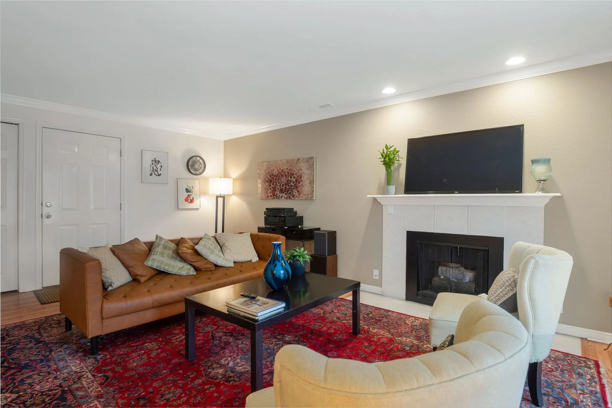 Living area featuring a tile fireplace, crown molding, and wood finished floors