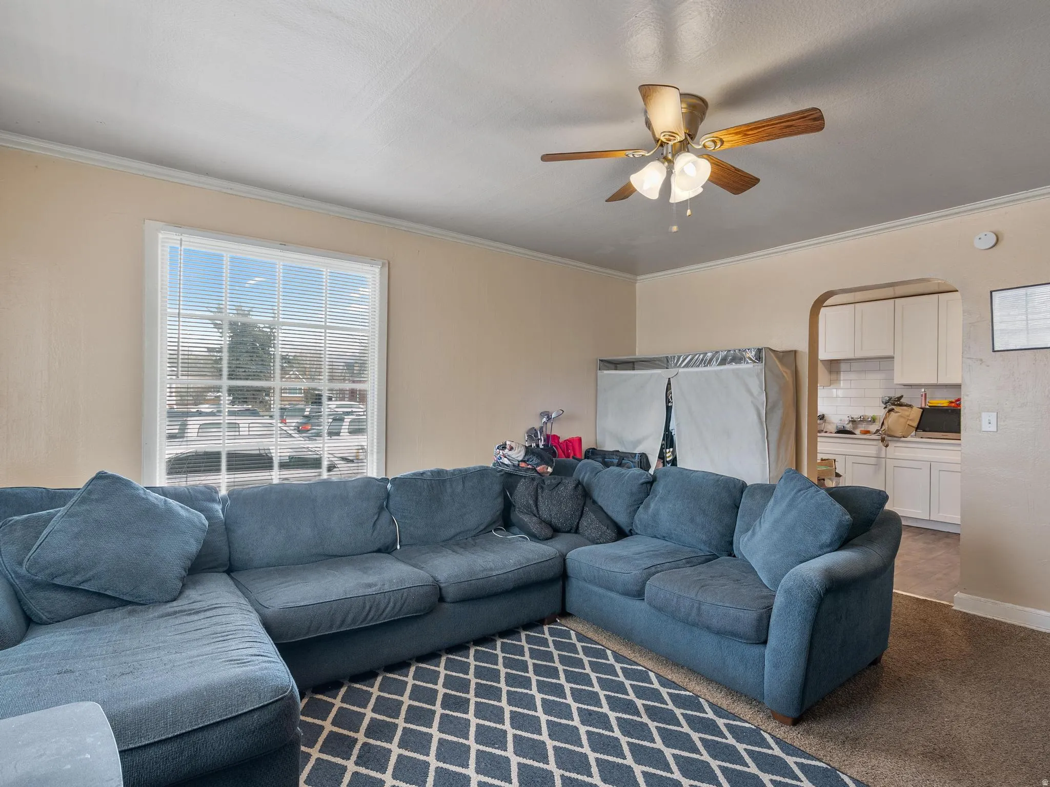#31 (Upstairs 1-bedroom): Living area with arched walkways, carpet floors, crown molding, and a ceiling fan