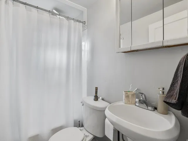 Full bathroom featuring toilet and shower / tub combo with curtain